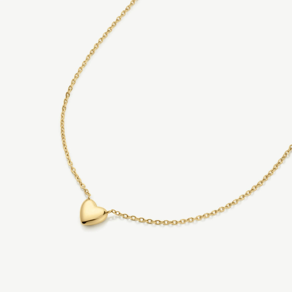 Delicate gold chain necklace with small polished heart pendant on white background