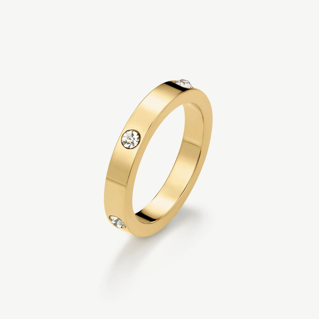 Gold band ring with evenly spaced clear gemstones on white background