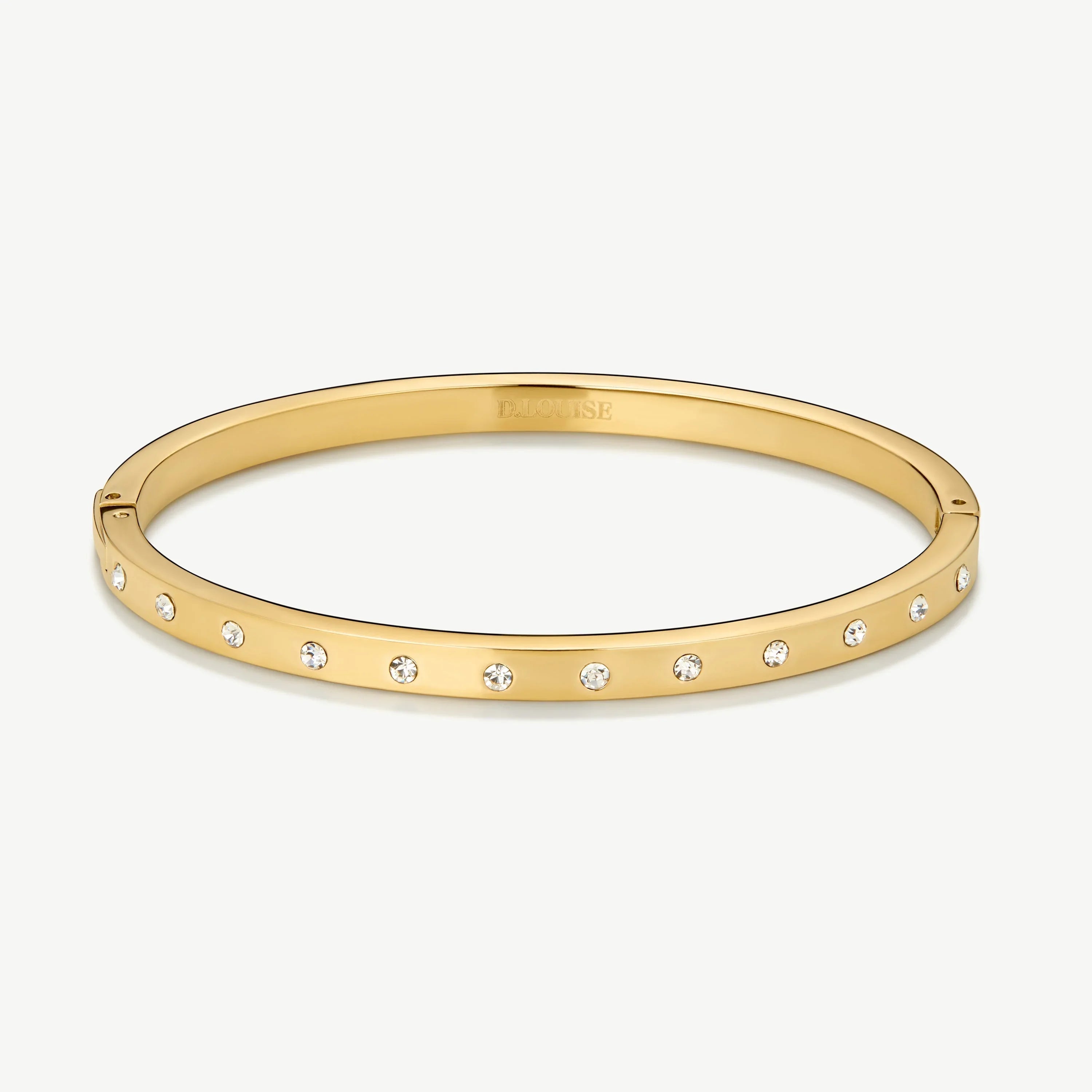 Gold bangle bracelet with evenly spaced small crystals on white background