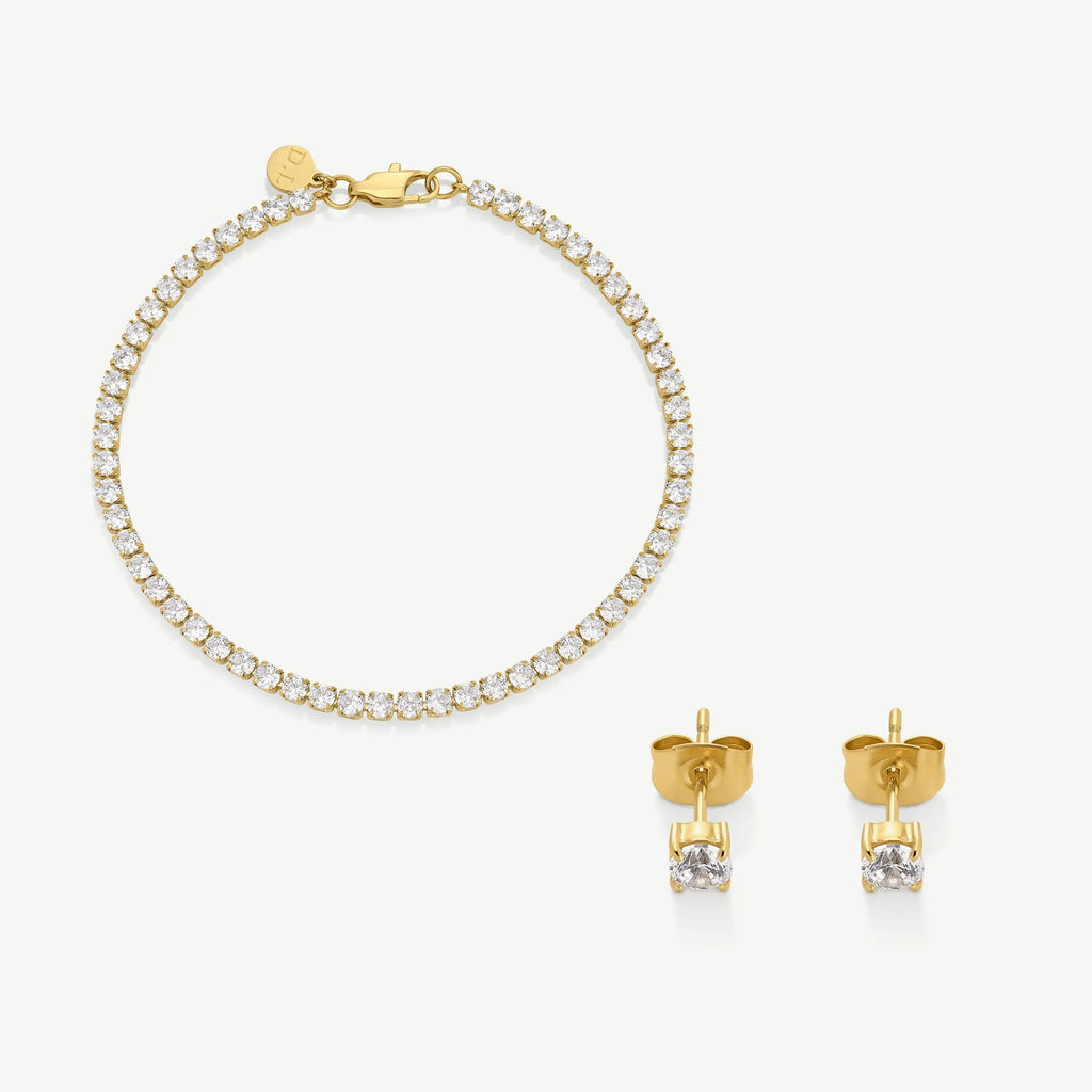 Gold tennis bracelet with clear stones and matching gold stud earrings on white background