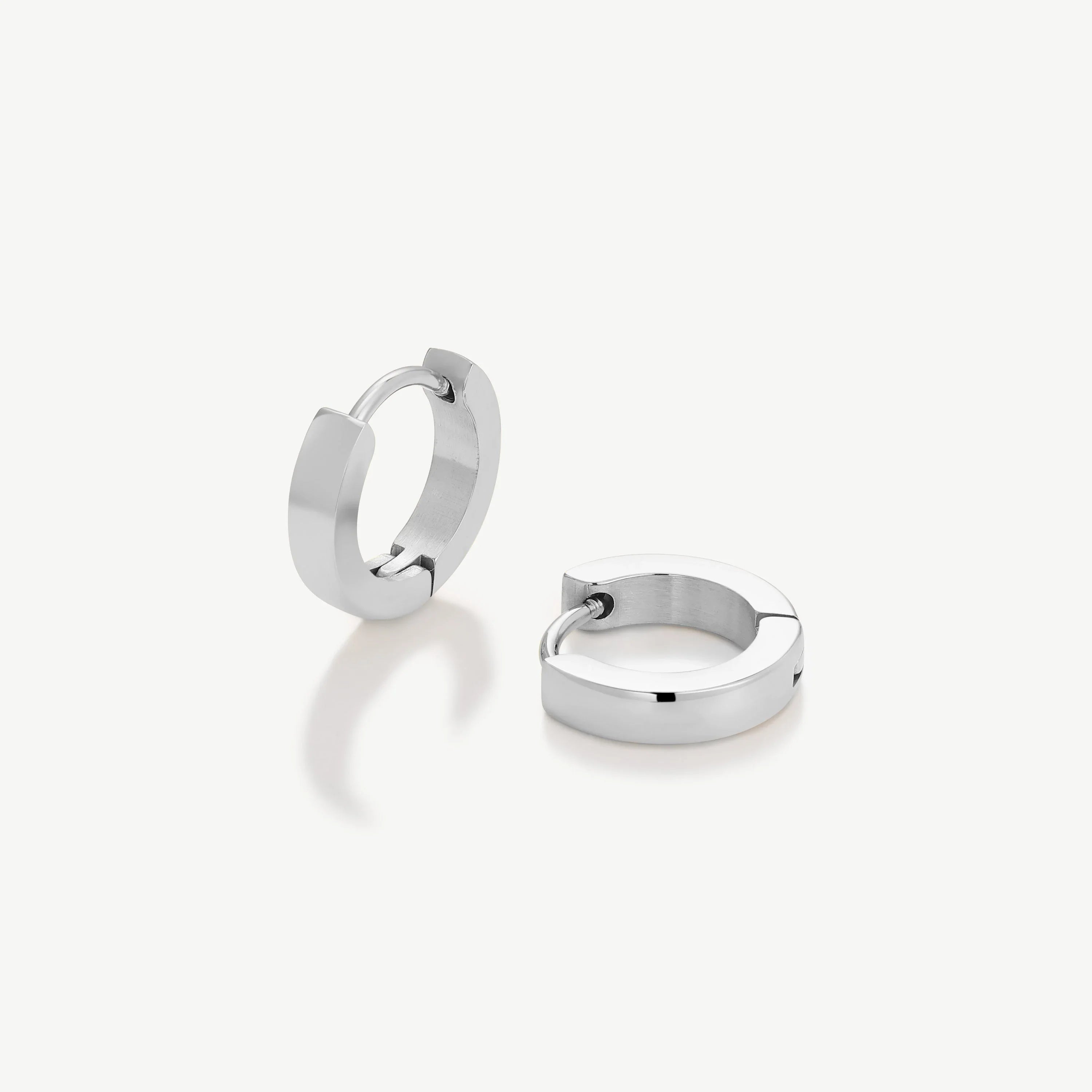 Pair of minimalist polished silver hoop earrings on white background