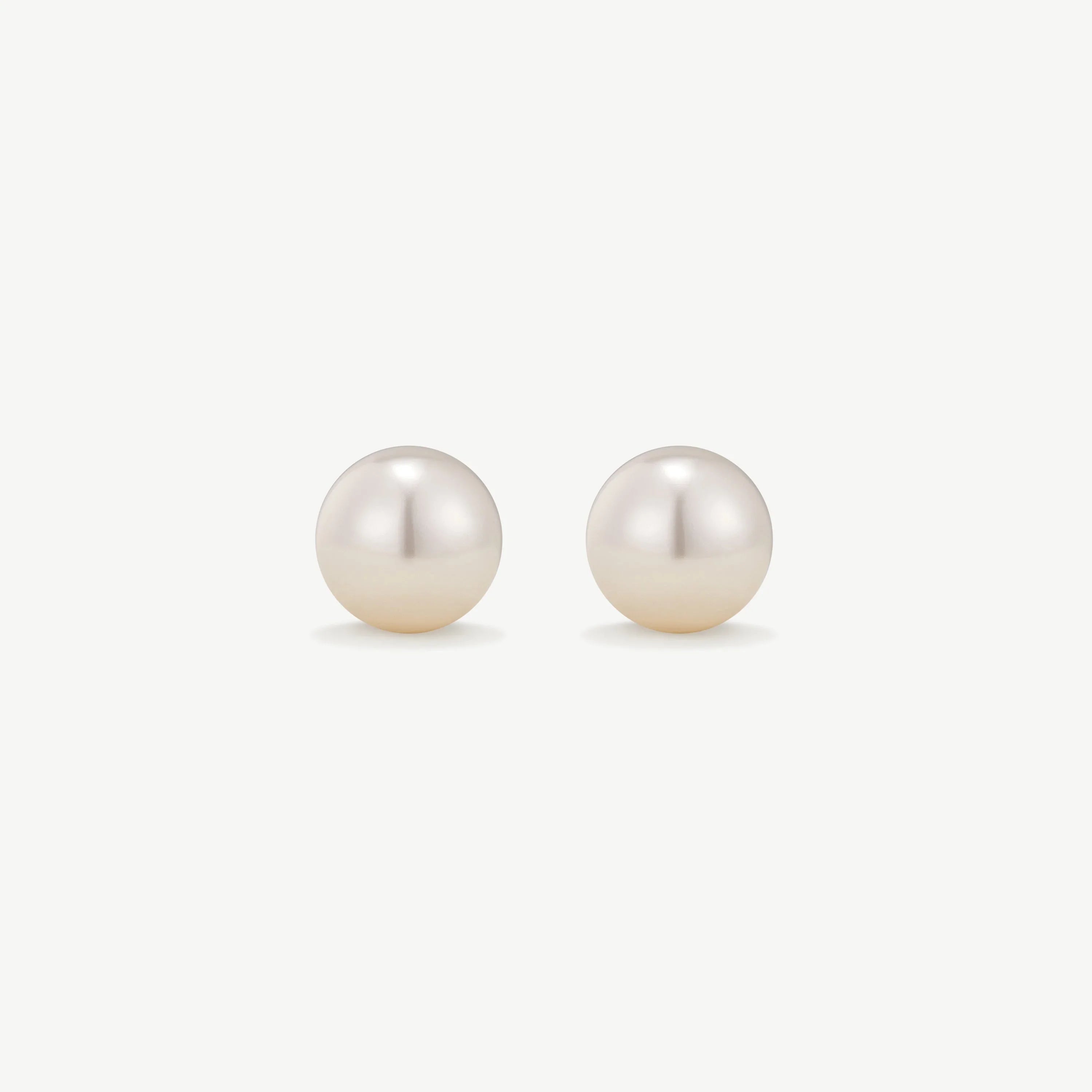 Pair of classic round white pearl stud earrings on white background