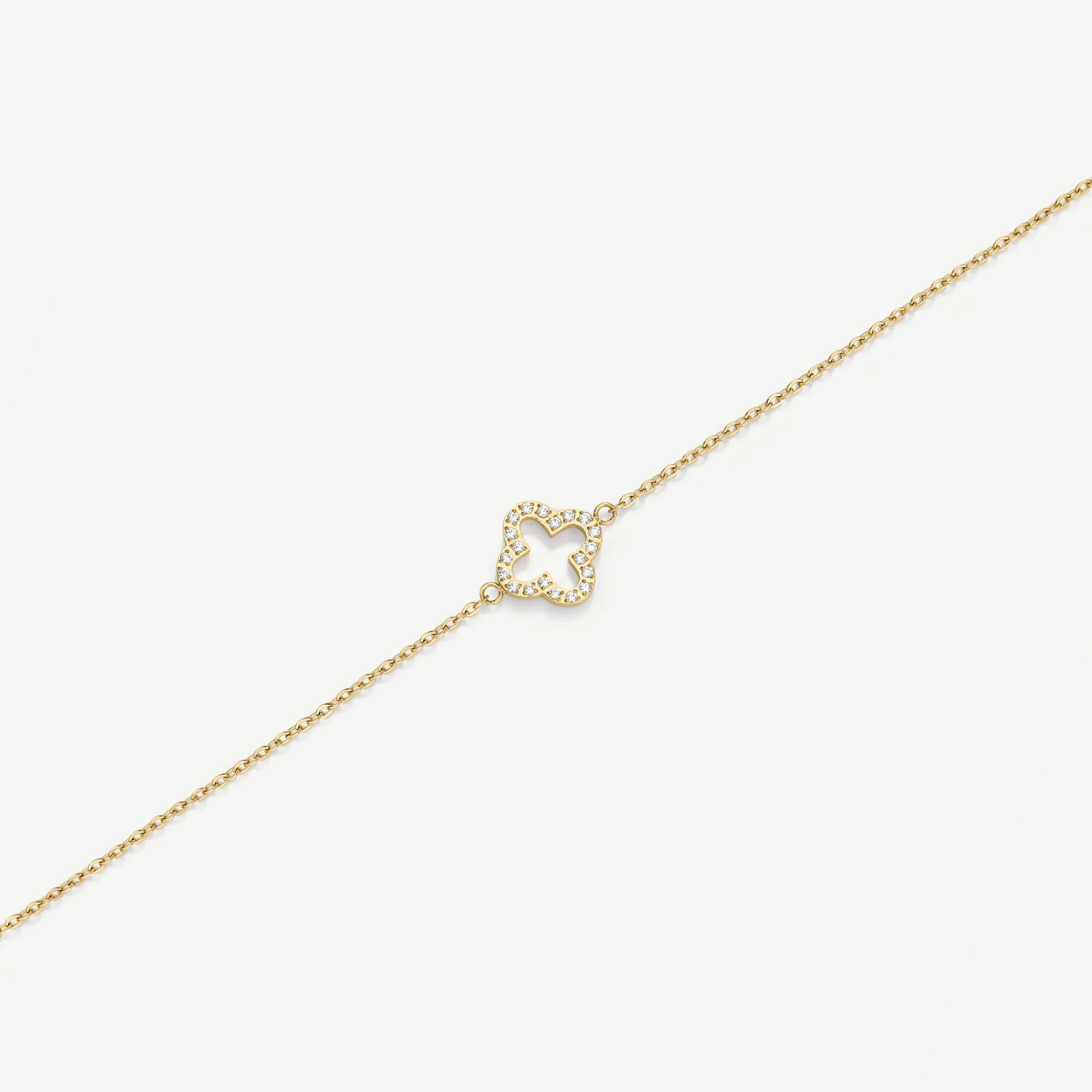 Gold chain bracelet with diamond-encrusted clover-shaped charm on white background