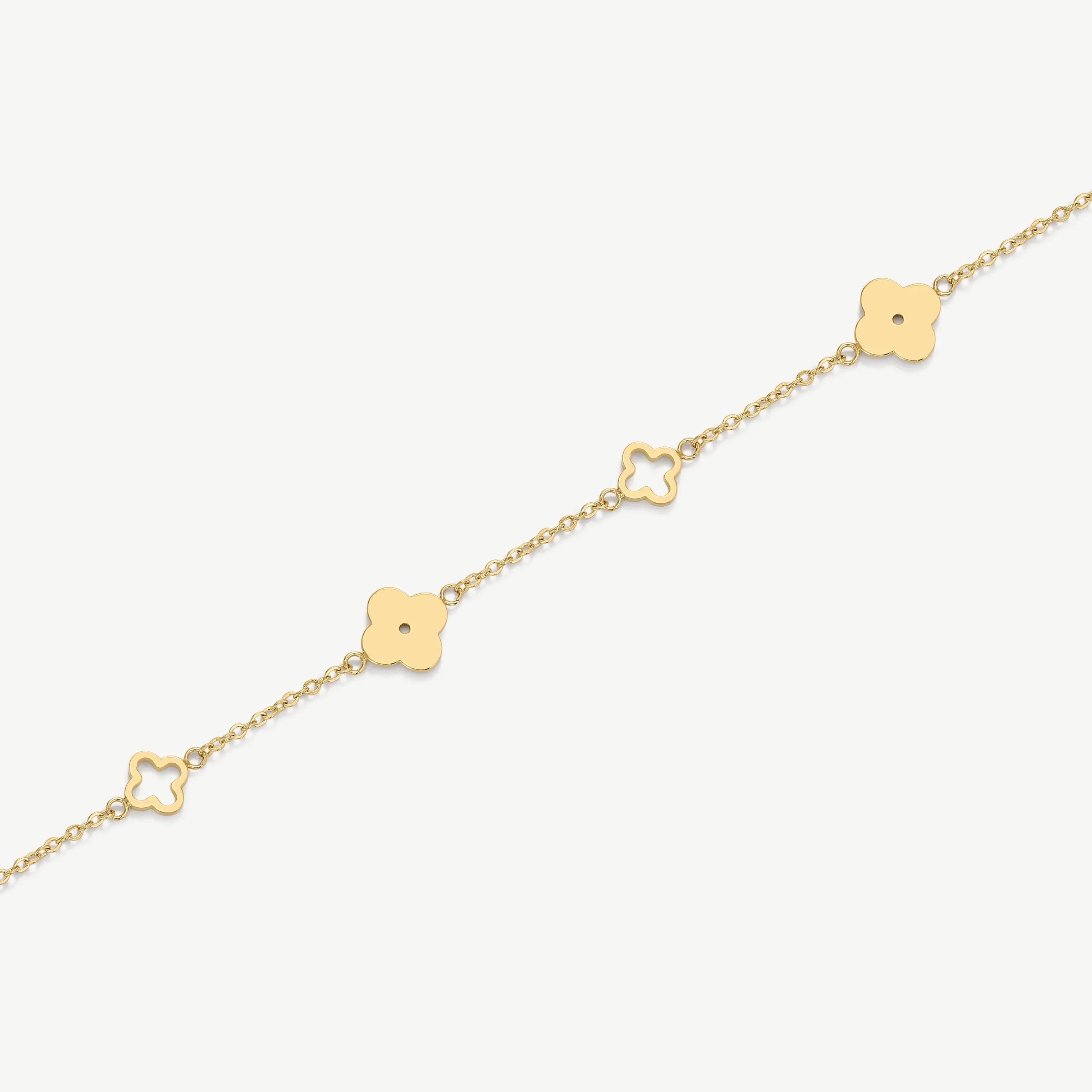 Delicate gold chain bracelet with alternating solid and hollow four-leaf clover charms on white background