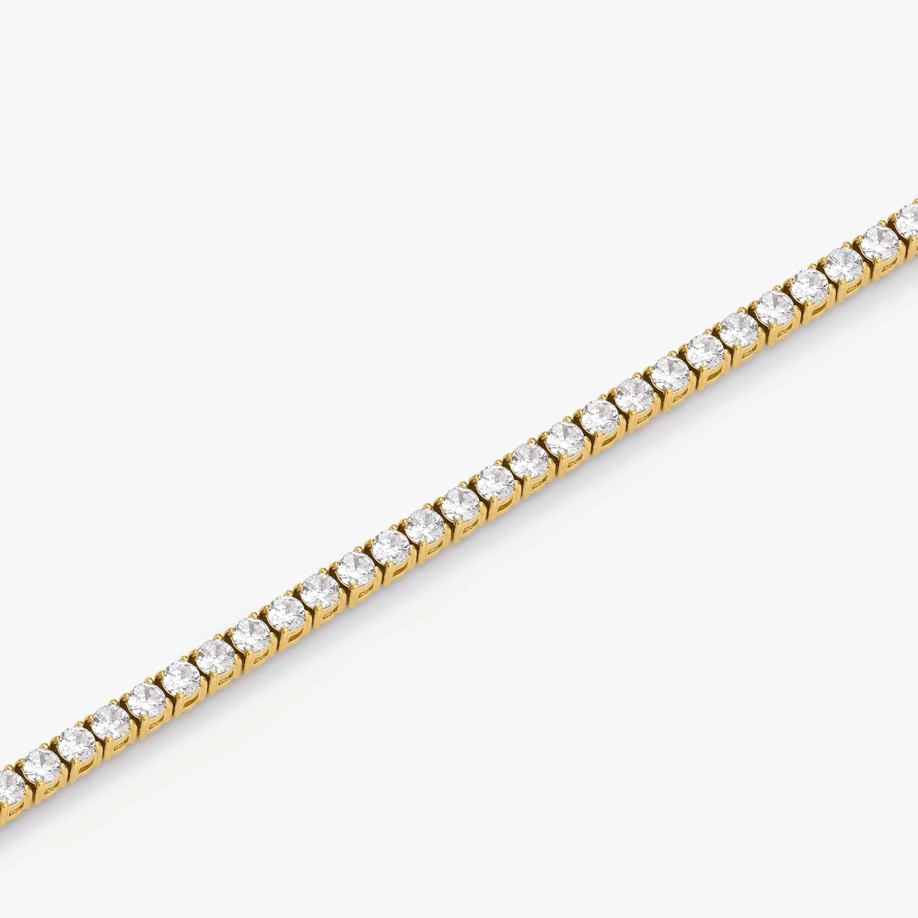 Close-up of gold tennis bracelet with round clear gemstones on white background