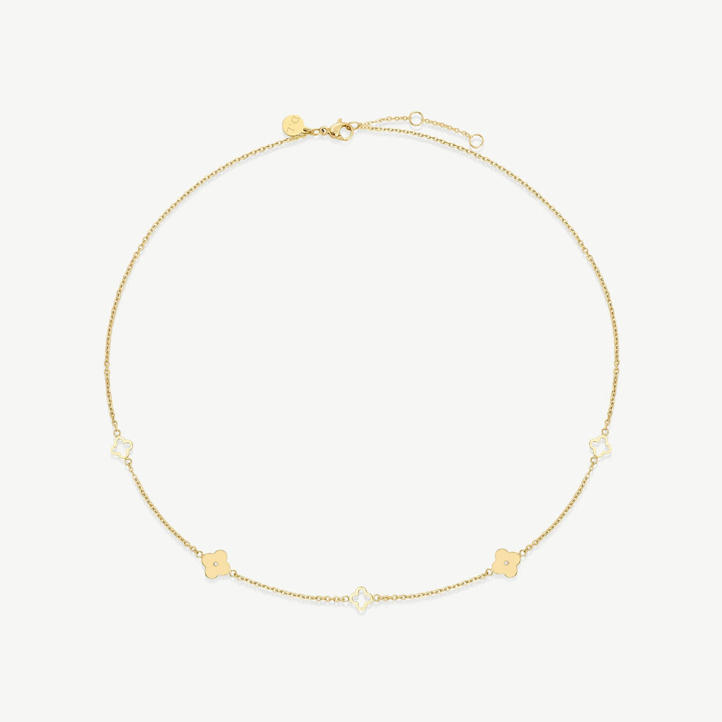 Delicate gold chain necklace with alternating solid and hollow four-leaf clover charms on white background