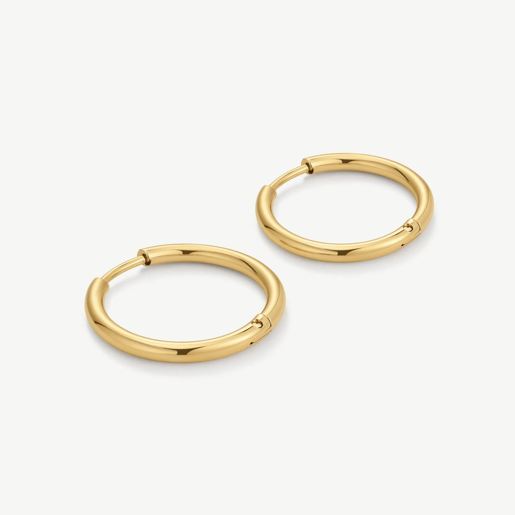Pair of polished gold hoop earrings with a seamless round design on white background