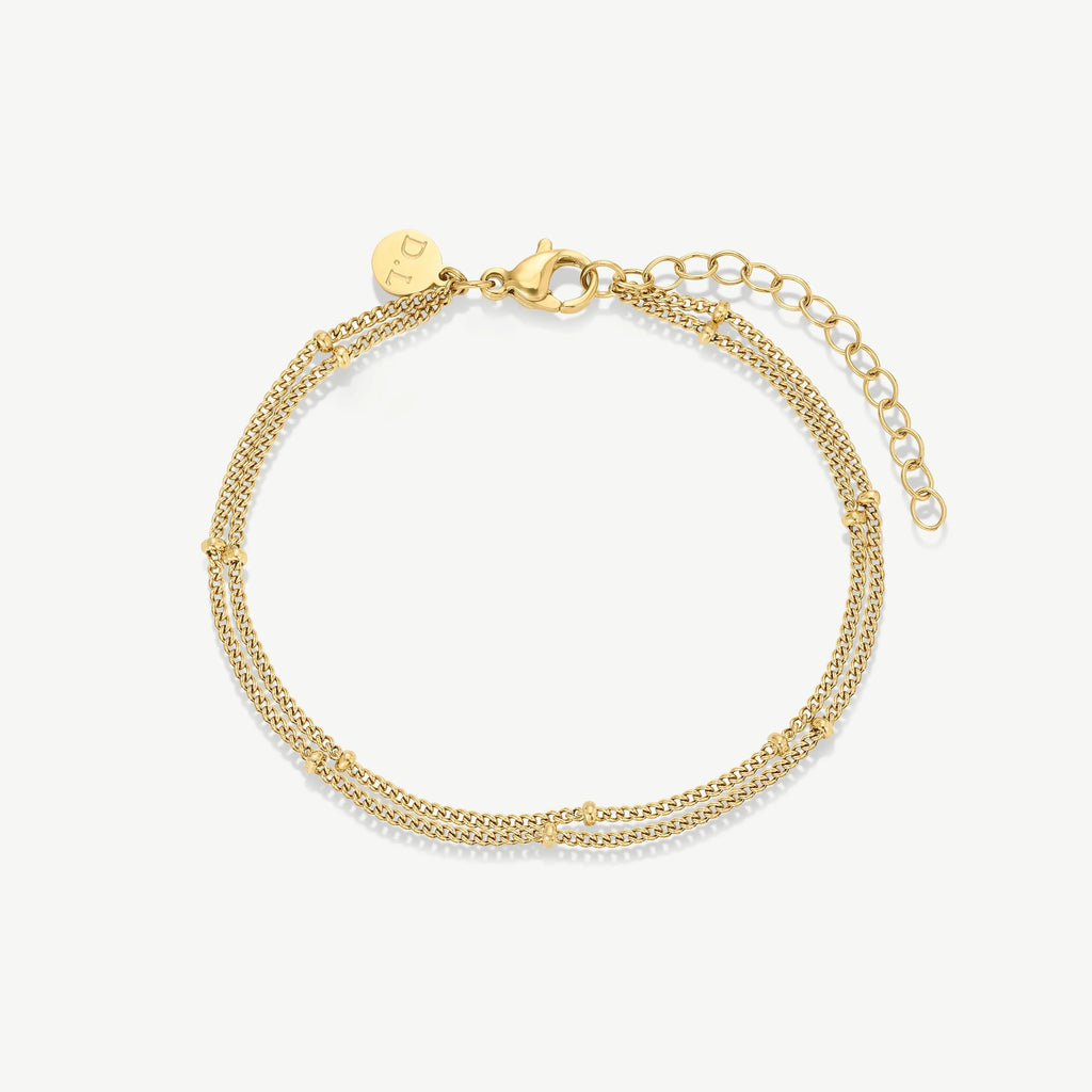 Delicate gold double chain bracelet with small beads and lobster clasp on white background