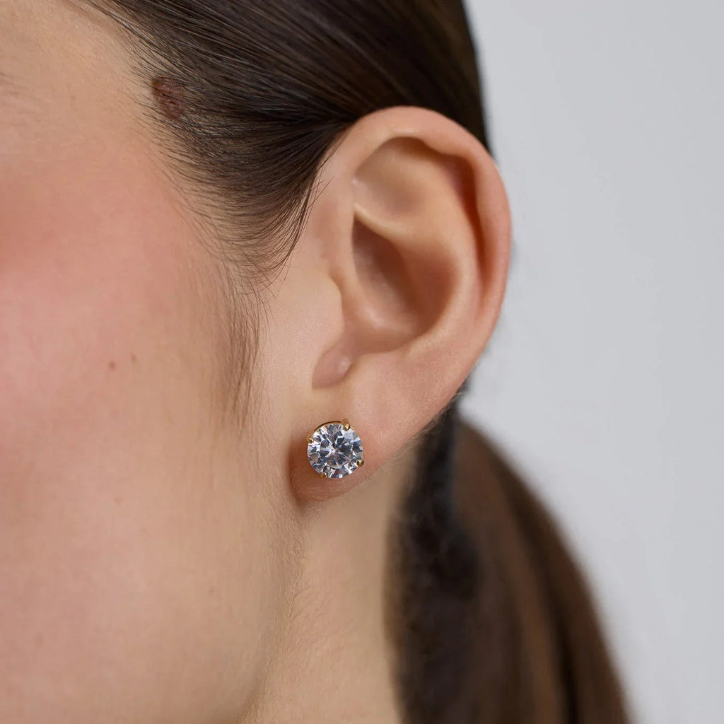 Close-up of ear wearing a large round brilliant diamond stud earring with gold prongs