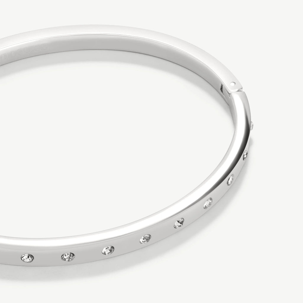 Silver bangle bracelet with embedded clear gemstones on white background