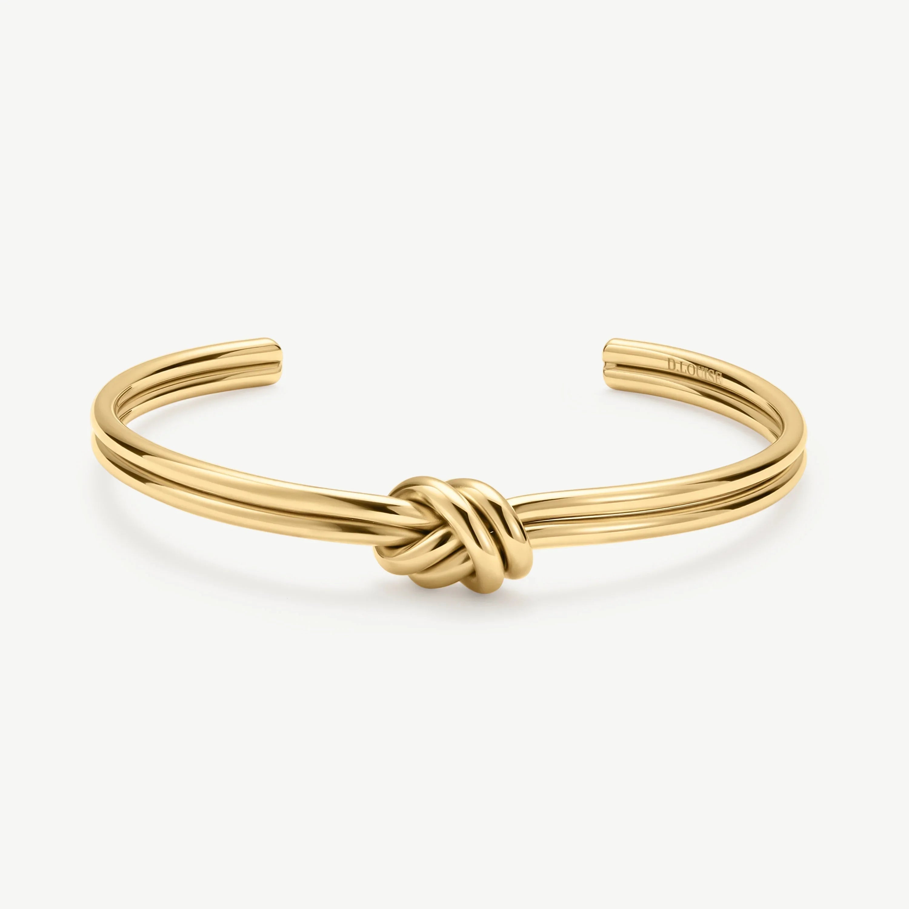 Gold-tone open cuff bracelet with a central knot design on white background
