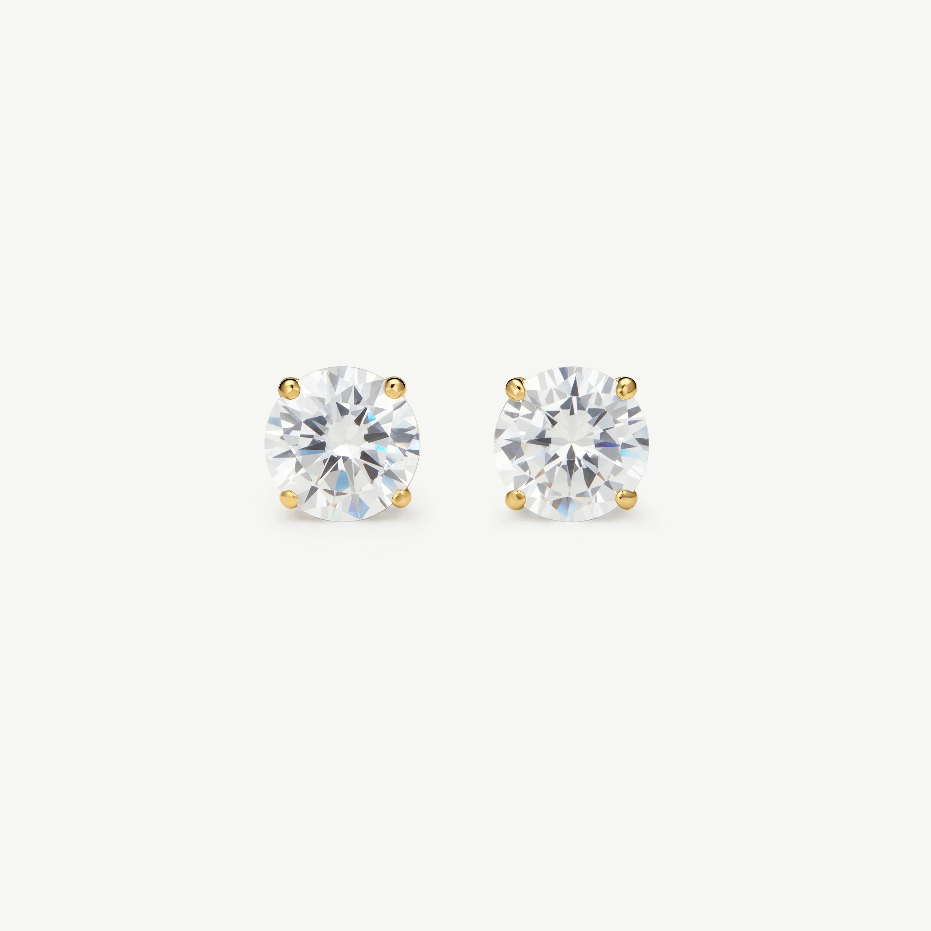 Pair of round clear diamond stud earrings set in four-prong yellow gold on white background