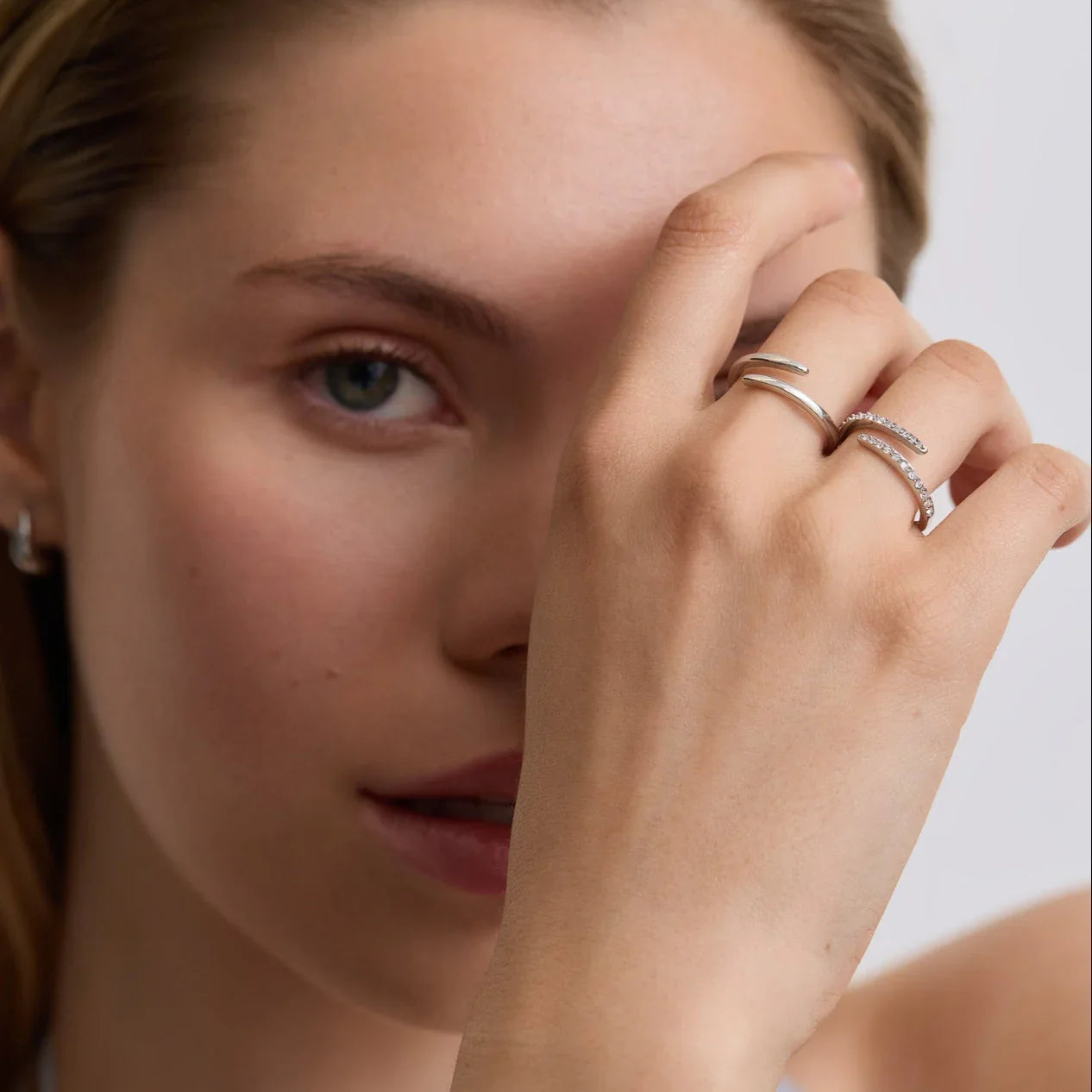 Close-up of a woman wearing silver wrap rings, one plain and one with small stones, on her fingers