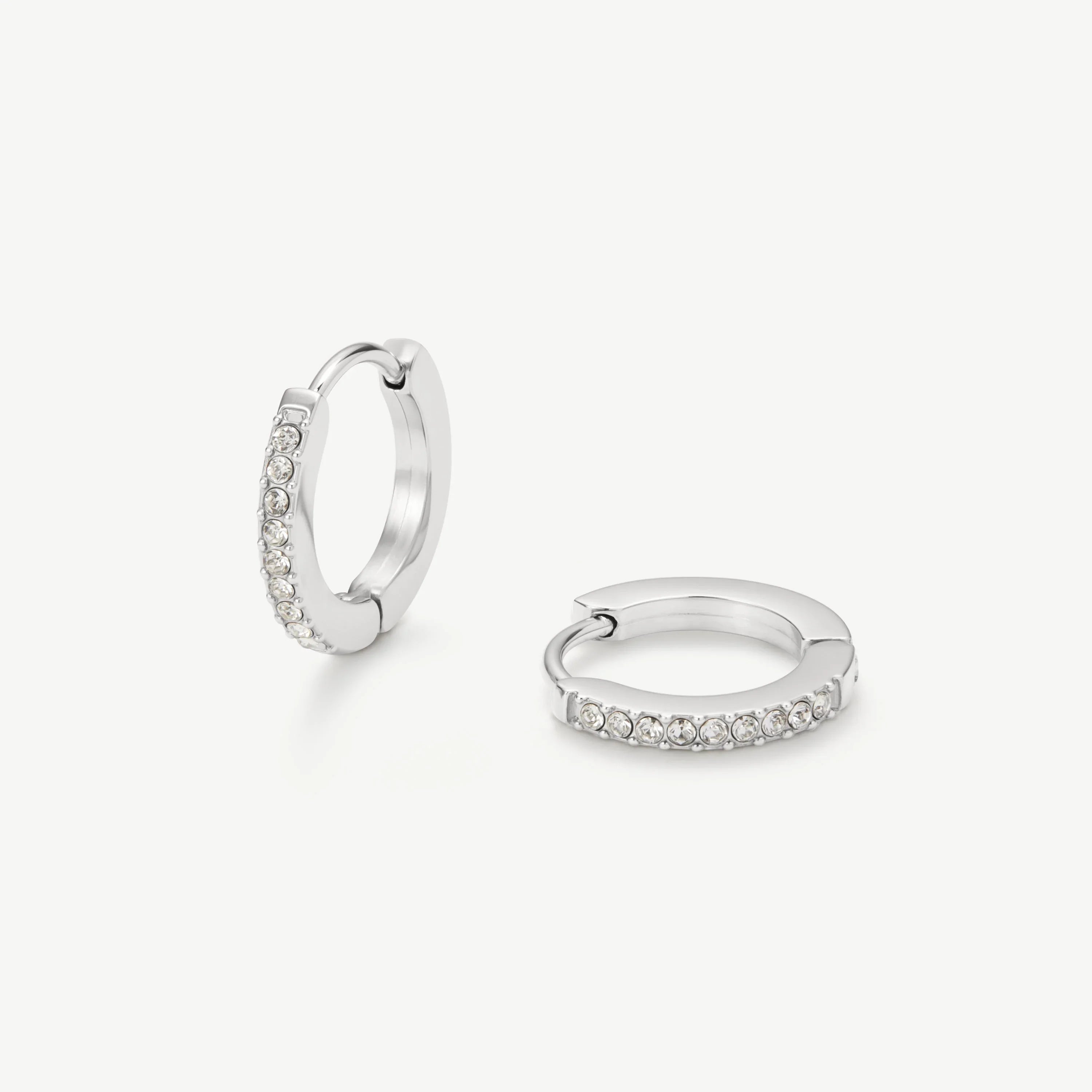 Pair of silver hoop earrings with clear crystals on a white background