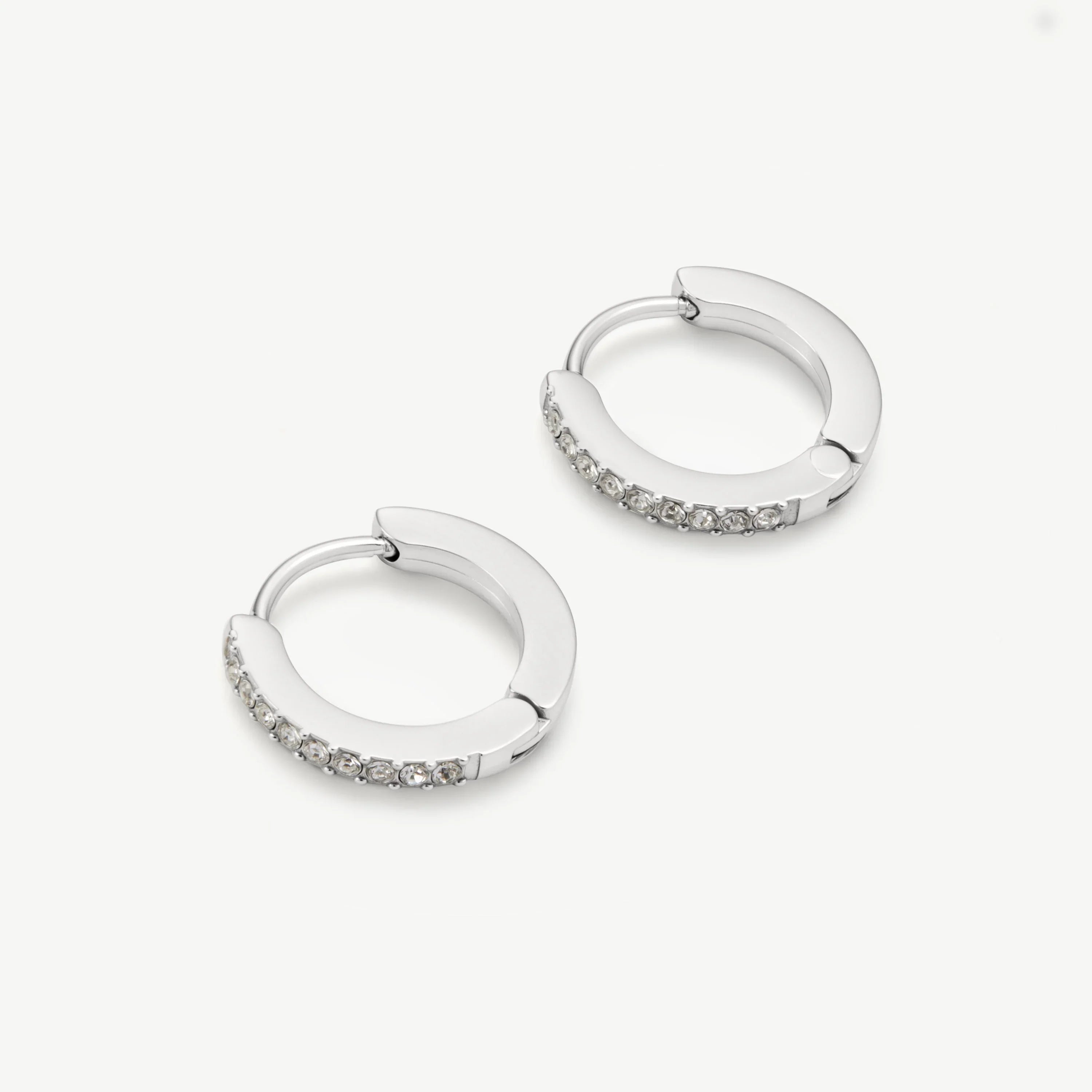 Silver hoop earrings with small clear crystals on a white background
